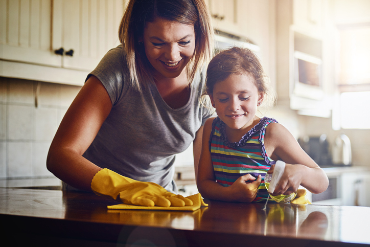 Photo of mother and daughter cleaning a kitchen surface together at home