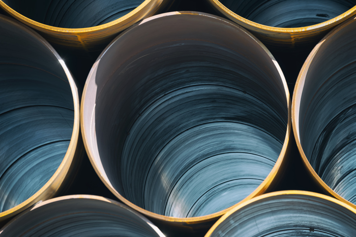 Photo of large industrial metal pipes, stacked several layers high